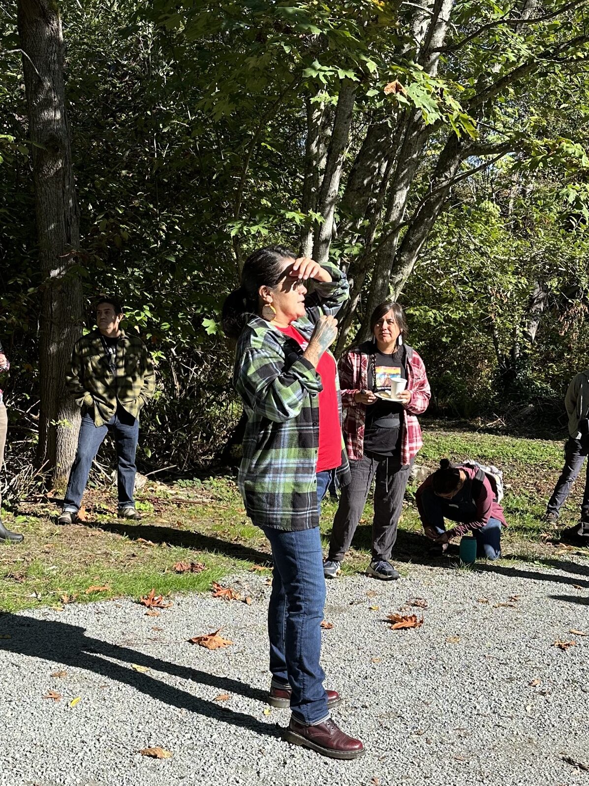An image of a person in a green plaid flannel and red shirt speaking to a group of people.