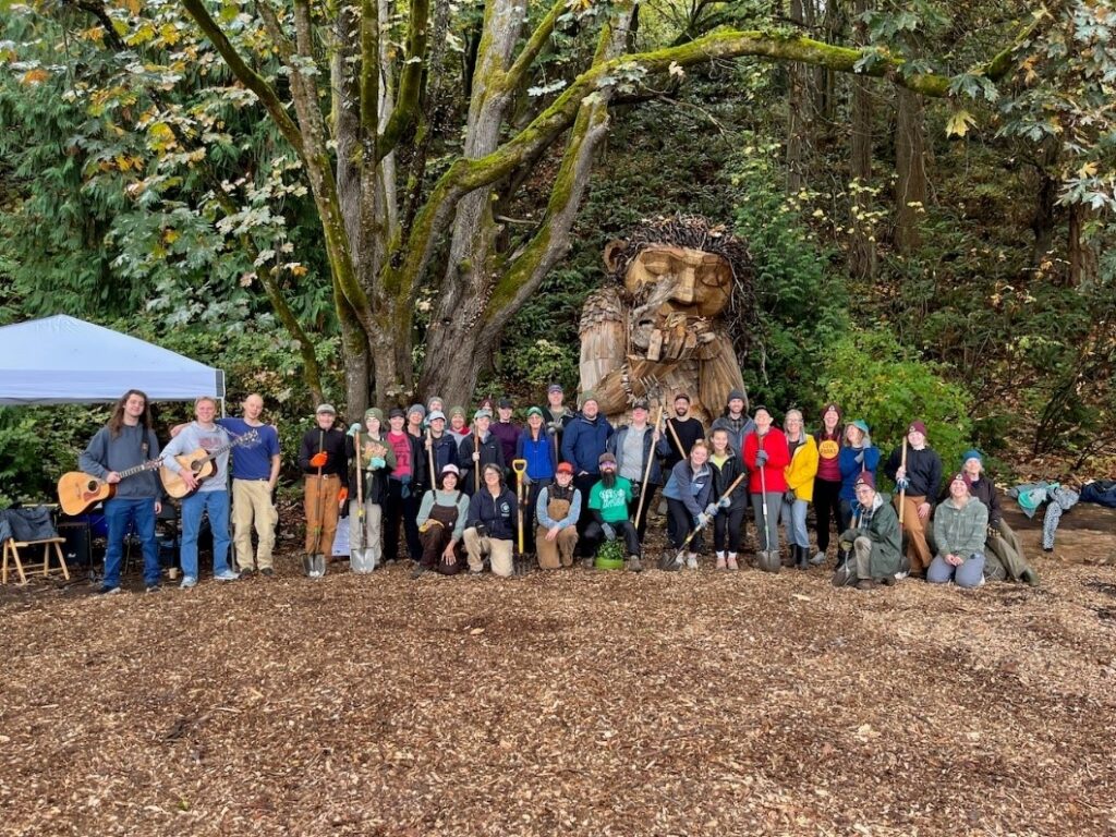 A huge group of people posing together with instruments, shovels, and other gear.