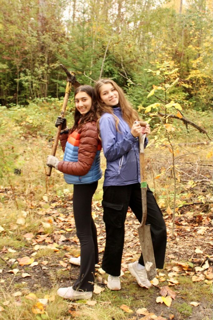 Two people standing back to back posing with a shovel and pickaxe.