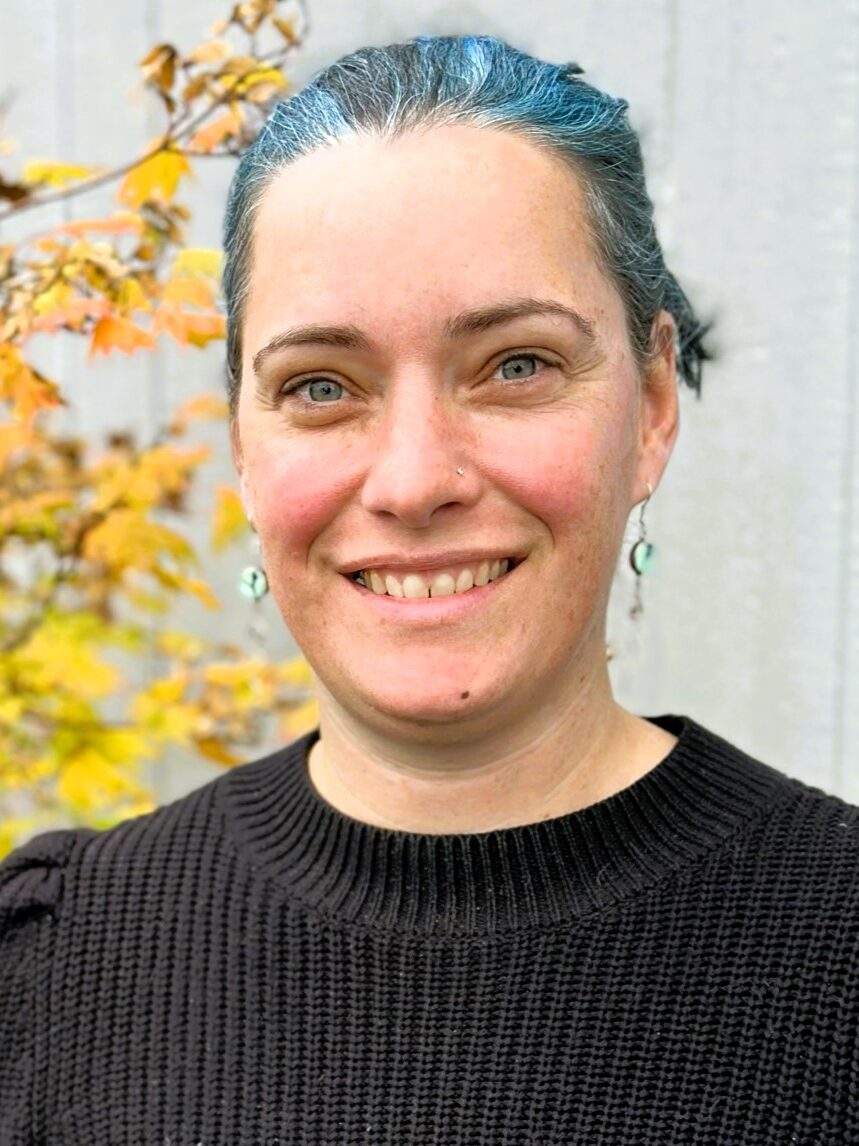 Danielle smiling in front of yellow tree foliage.